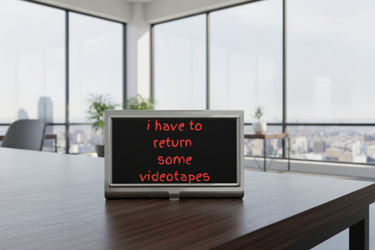 Business card holder with the text 'i have to return some videotapes' in red font on a black background.